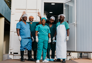 Surgical staff outside a mobile clinic, following successful surgery.