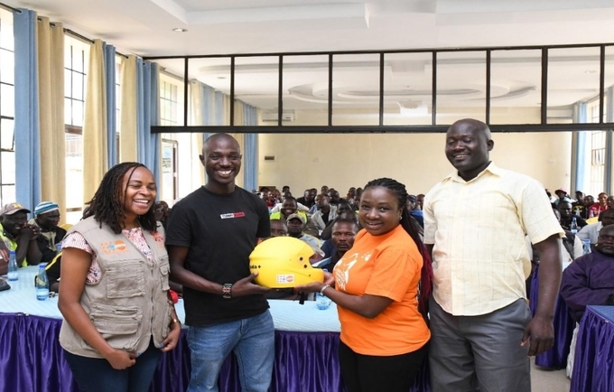 UNFPA staff present a helmet to Boda-Boda Association of Kenya Chair Kevin Mubadi in Kisumu County.
