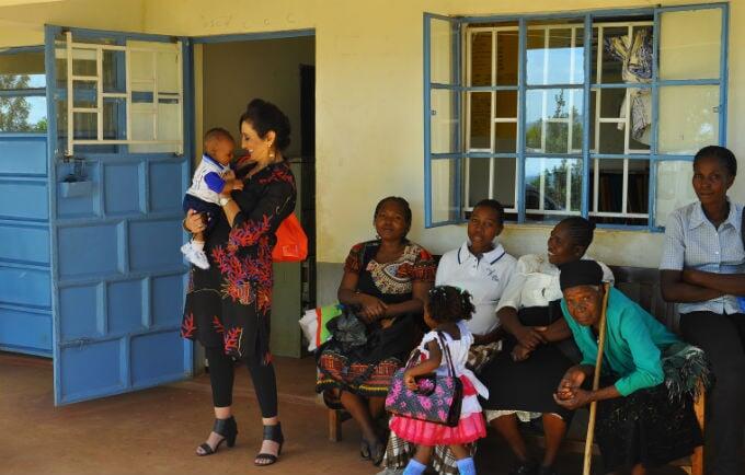 Honorary Ambassador Ms. Gina Din greets a mother and her baby at the Uhiri Health facility during her visit