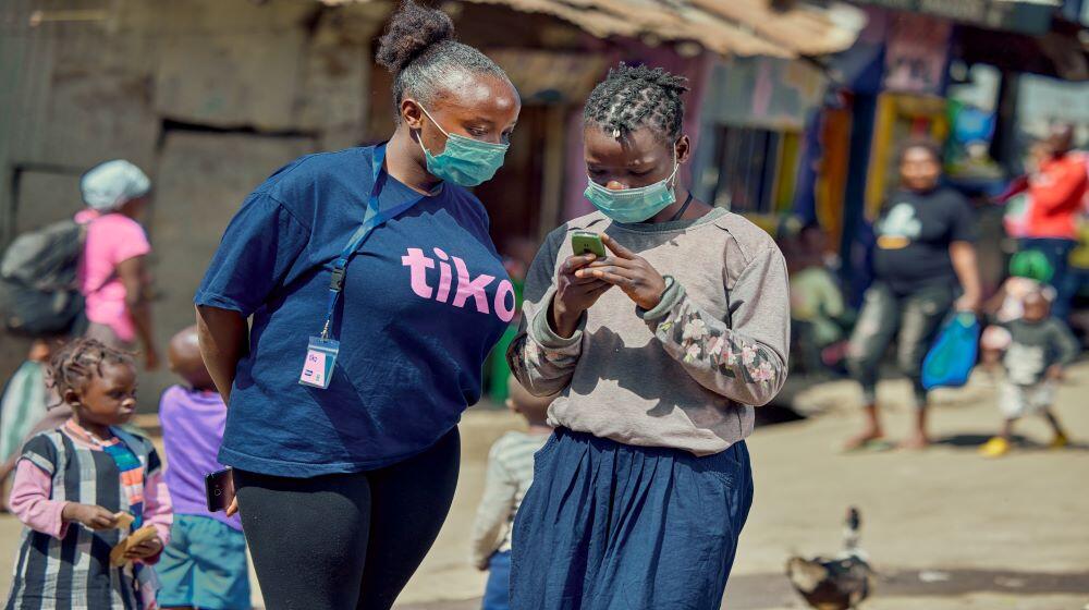 Community mobiliser Joyce Katheu helps a girl enroll on the Tiko platform in Mathare Informal Settlement, Nairobi. Photo: © Trig